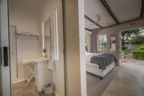 a bedroom with a bed and a sink and a mirror at Graskop Hotel in Graskop
