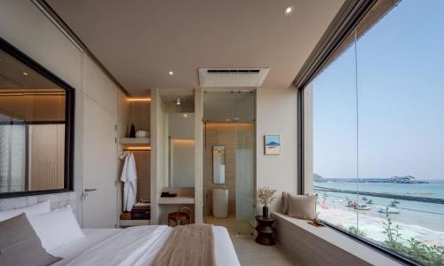 a bedroom with a large window with a view of the ocean at POV Pool Villas in Ko Larn