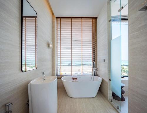 a bathroom with a white tub and a sink at POV Pool Villas in Ko Larn