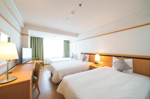 a hotel room with two beds and a desk at 琉球オリオンホテル 那覇国際通り in Naha