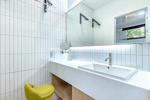 a bathroom with a sink and a yellow chair at The Bay Jeju Resort in Seogwipo