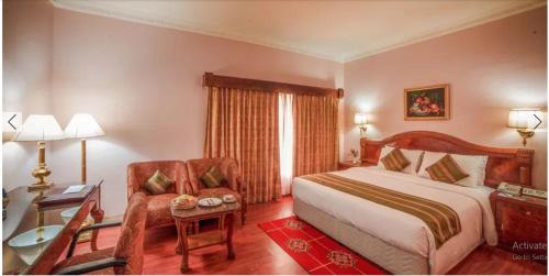 a bedroom with a bed and a desk and a chair at Raj Park Hotel Chennai in Chennai