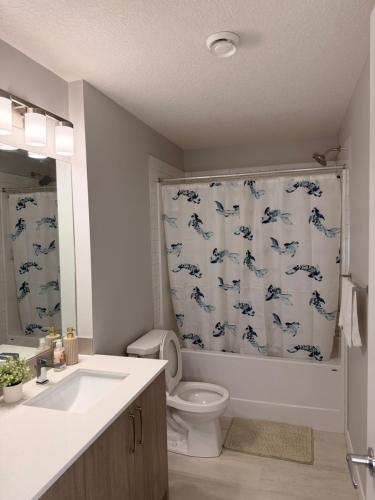 a bathroom with a toilet and a shower curtain with dolphins at Casa Gabriel in YYC