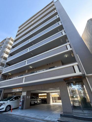 a tall building with a car parked in a parking lot at OUCHI HOTEL Peace Memorial Park in Hiroshima
