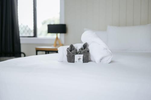 a teddy bear sitting on a bed with towels at Rix Hotel Motel in Charters Towers