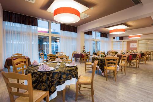a dining room with tables and chairs and windows at Medjugorje Hotel & Spa in Međugorje