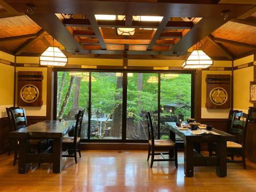 a dining room with a table and chairs and a large window at Hotakajo in Azumino