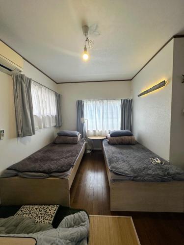 a room with two beds and a table with a window at Tsushima White House in Tsushima