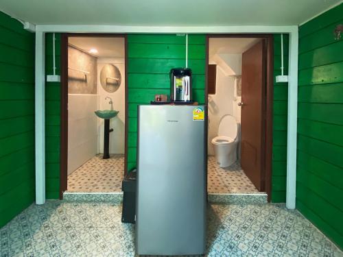 a green bathroom with a refrigerator and a toilet at เรือนเงินตรา in Ban Khlong Hok
