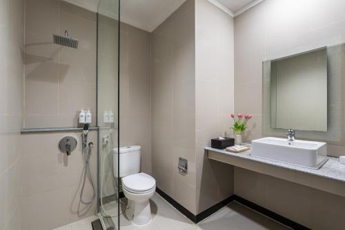 a bathroom with a toilet and a sink and a mirror at Bentani Hotel & Residences Cirebon in Cirebon