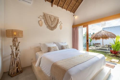 a bedroom with a bed and a large window at LYS Home in Jimbaran