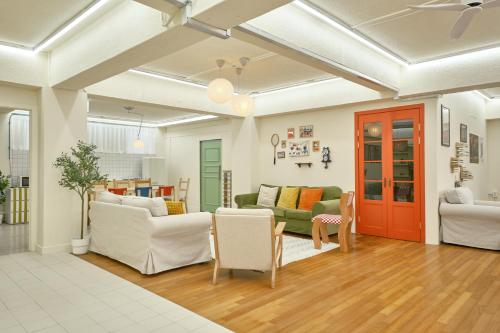 a living room with white furniture and a red door at The FLOW HOUSE in Suwon