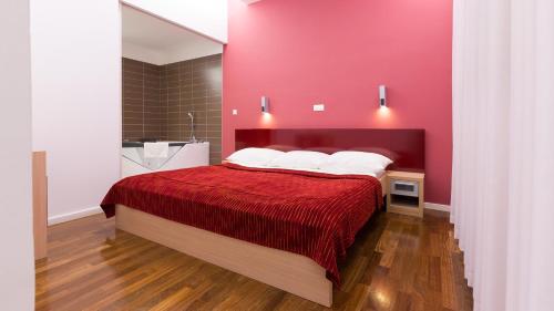a bedroom with a bed with a red wall at Dream Hotel in Velika Gorica