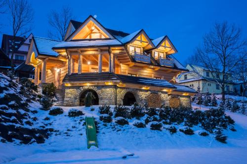 a large wooden house in the snow at night at udanypobyt Dom Forest Prestige House in Rzepiska