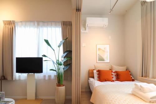a bedroom with a bed with orange pillows and a television at Ken's Place Minami-Azabu in Tokyo