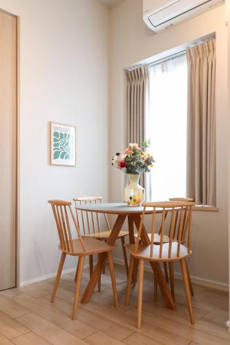 a dining room table with two chairs and a vase with flowers at Ken's Place Minami-Azabu in Tokyo