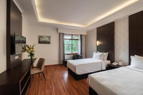 a hotel room with two beds and a desk at Bentani Hotel & Residences Cirebon in Cirebon