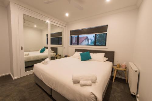 una camera da letto con un grande letto bianco e due finestre di The Bright House a Bendigo