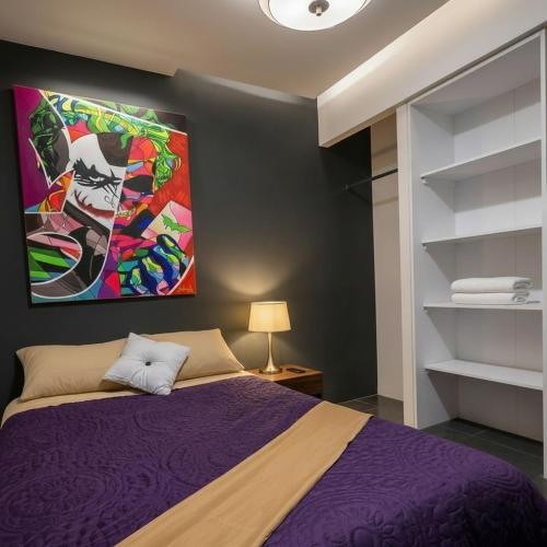 a bedroom with a purple bed with a painting on the wall at Casa providencia suites in Guadalajara