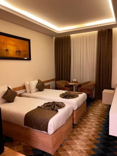 a hotel room with two beds and a table at فندق البرج الابيض - White Tower Hotel in Ōlmush