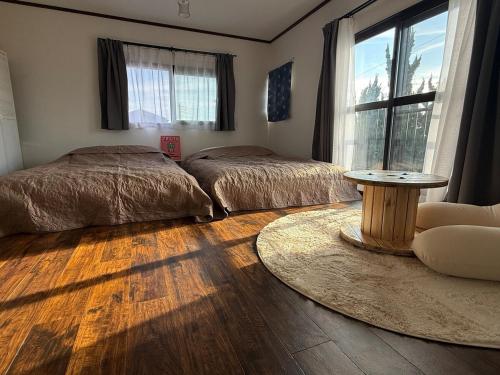 a bedroom with two beds and a table in it at パノラマスター白子-Panoramastars Shirako-星降る夜の貸切ステイ in Shirako