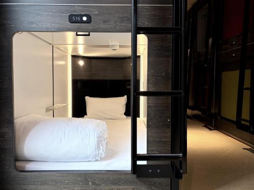 a bedroom with a bed inside of a glass door at Capsule Hotel Suzumoriya in Tokyo