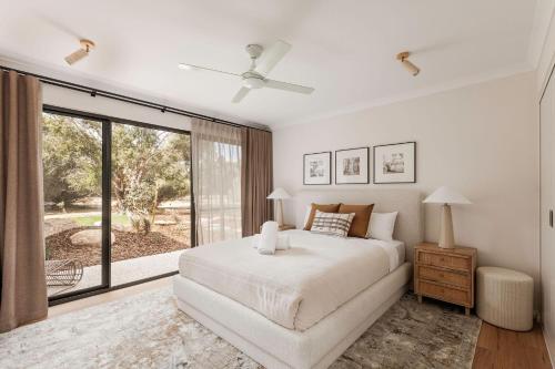 a white bedroom with a bed and a large window at Wilyabrup Waters Retreat in Wilyabrup