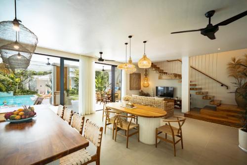 a dining room and living room with a table and chairs at Casa Capucine Uluwatu in Uluwatu