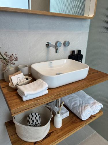 a bathroom sink on a wooden shelf with towels at Driftwood Studio in Mount Martha