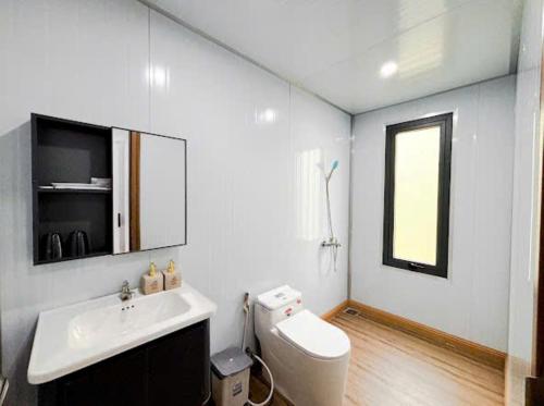 a bathroom with a toilet and a sink and a window at ANORA Homestay in Vũng Liêm