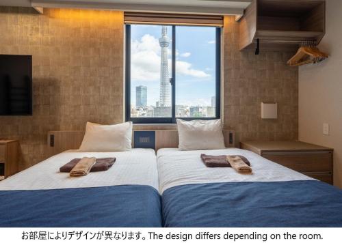 two beds in a room with a view of a city at stayme THE HOTEL Asakusa Riverside in Tokyo