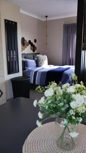 ein Schlafzimmer mit einem Bett und einem Tisch mit Blumen in der Unterkunft Two Lakes in Bettyʼs Bay