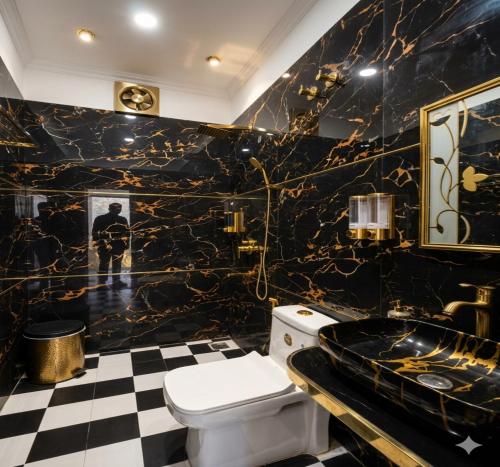a black and gold bathroom with a toilet and a sink at Qcent Bairagarh Resort Rishikesh in Mohan Chatti