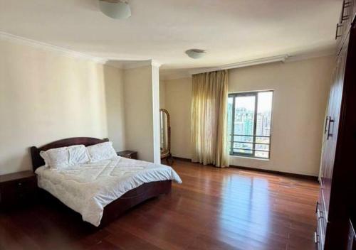 a bedroom with a bed and a large window at Luxury Oasis-May Real Estate Apartments in Addis Ababa