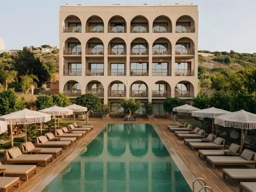 a hotel with a swimming pool and chairs and a building at LSaranda House Cesme 16 Adult Only in Çeşme