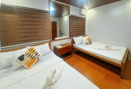 two beds in a small room with wooden floors at RedDoorz at Balai Malinawon Siargao in General Luna