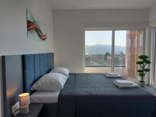 a bedroom with a large bed with a large window at Holiday house VILLA PATRICK with pool, jacuzzi and sauna in Kornić