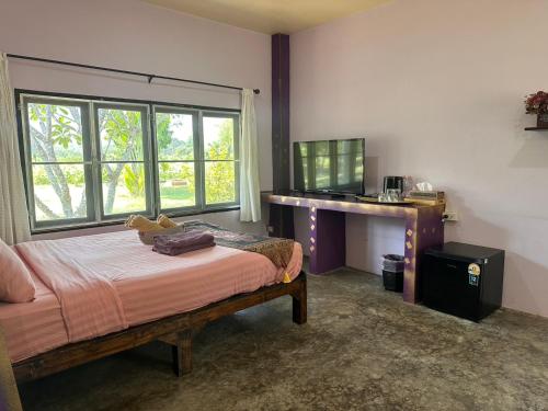 a bedroom with a bed and a desk and window at TheOrientalVillage in Ban Pao Sam Kha