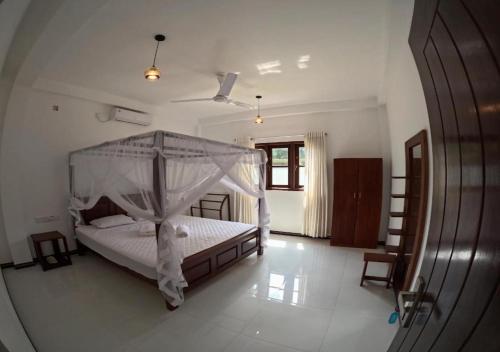 a bedroom with a white bed with a canopy at Shade Villa in Galle