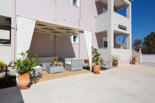 an outdoor patio of a white building with potted plants at Veneti Apartments - Corfu Serene Getaways in Sidari