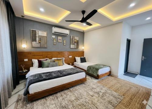 a bedroom with two beds and a ceiling fan at Qcent Bairagarh Resort Rishikesh in Mohan Chatti