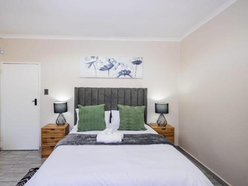 a bedroom with a large bed with green pillows at Olive House in Brackenfell
