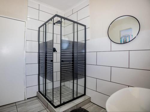 a glass shower in a bathroom with a mirror at Olive House in Brackenfell