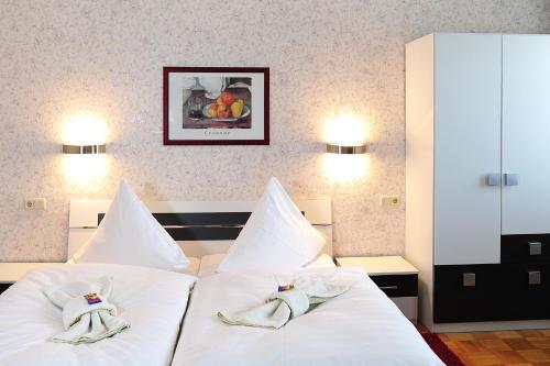 Landhotel Plauen - Gasthof Zwoschwitz في بلاوين: غرفة نوم بسريرين بيض عليها مناشف