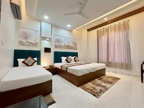 a bedroom with two beds and a tv in it at SR Palace - Best Hotel in Vrindavan Near Prem Mandir and Iskcon Temple with Private Parking in Vrindāvan