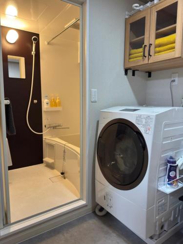 a washing machine in a bathroom with a shower at 長期滞在 HYGGE HOUSE 駐車無料 JR北柏駅徒歩2分 フルキッチン 洗濯乾燥機 高速Wi-Fi アメニティ完備 上野30分 成田or羽田空港60分 in Kashiwa
