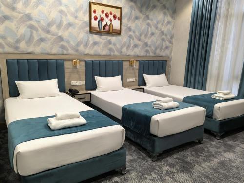 a room with three beds with towels on them at Chilonzor Hotel in Tashkent