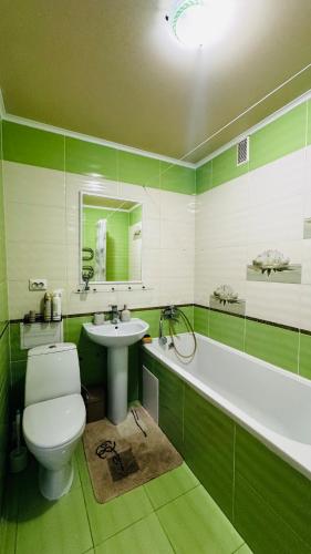 a green and white bathroom with a toilet and a sink at Vinnytsia, Vyshenka in Vinnytsya