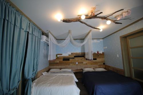 a bedroom with three beds and a branch on the ceiling at Gyeongju Eowoolim Pension in Gyeongju
