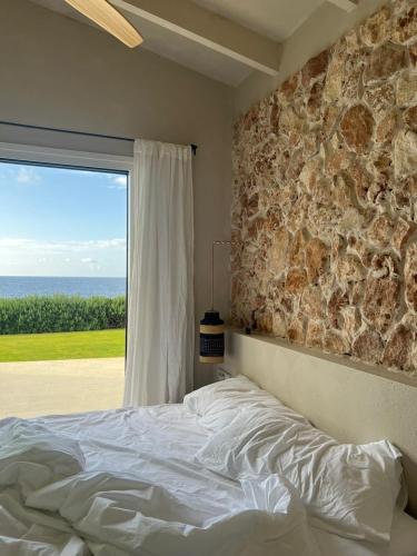 a bed in a bedroom with a stone wall and a window at Binilua in Binibeca